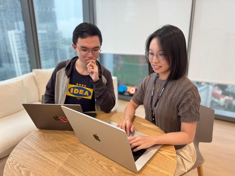 Two Airwallex team members work together on their laptops in the company’s office
