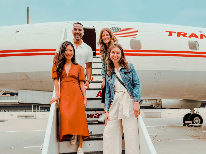 Alma team members posing for photo on staircase leading up to airplane