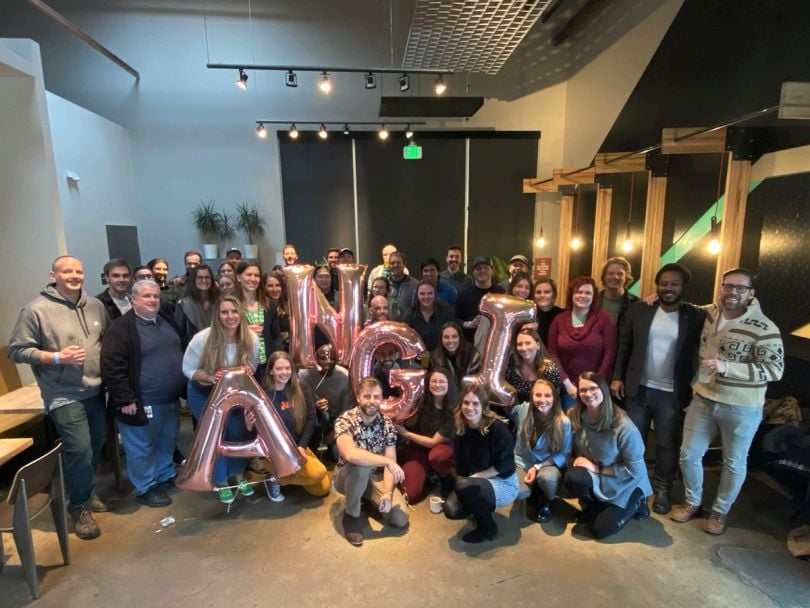 Angi group photo with team members holding balloons that spell ANGI