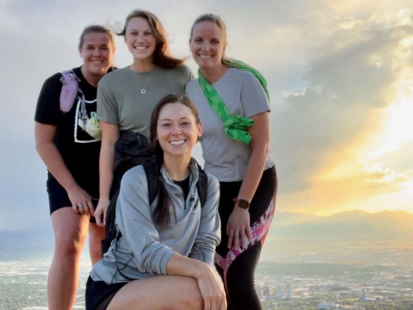 Four Navan women employees standing on a hill overlooking an urban landscape at sunset