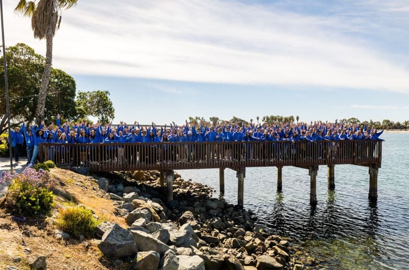 BetterCloud team members wearing blue shirts standing on a pier over the water