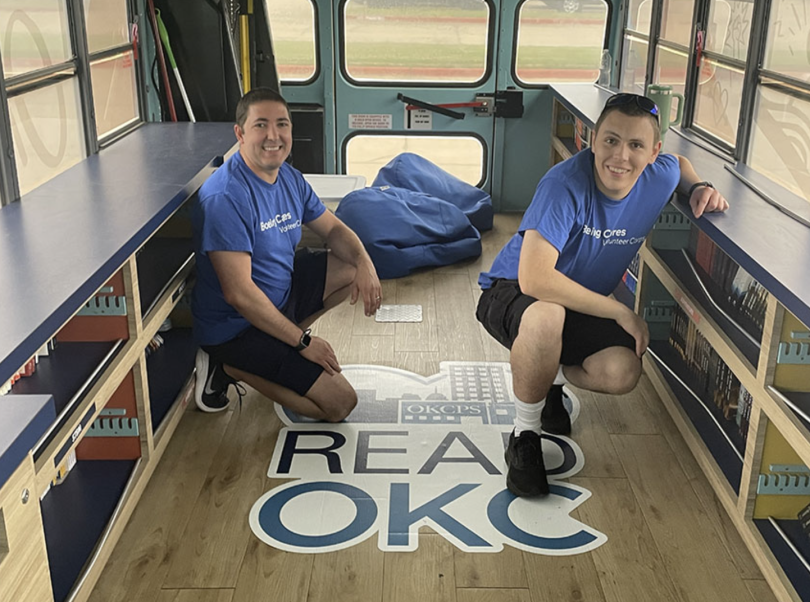 Chris Silvano and a teammate pose for a photo on a mobile library during the company’s Liftoff for Learning
