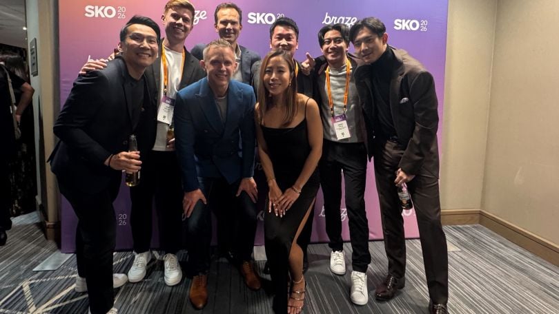 A photo of Braze employees posing together in front of a banner
