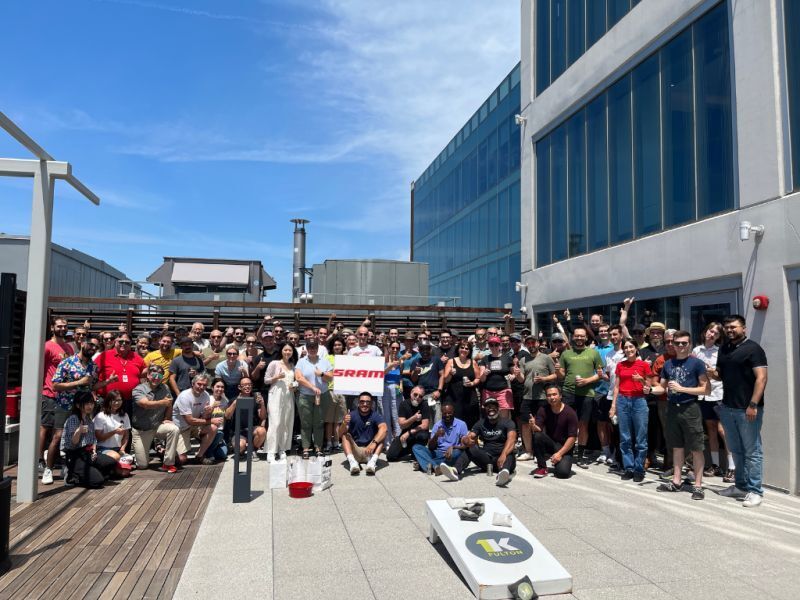 A large gathering of SRAM employees stand in front of a building