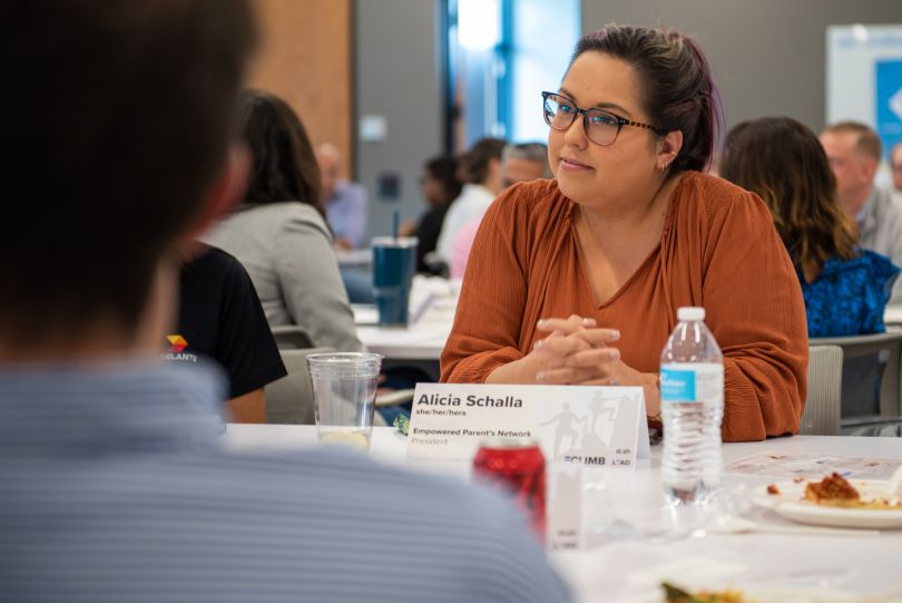 DISH team member Alicia Schalla sits in a thoughtful pose behind her nametag at a professional development event.