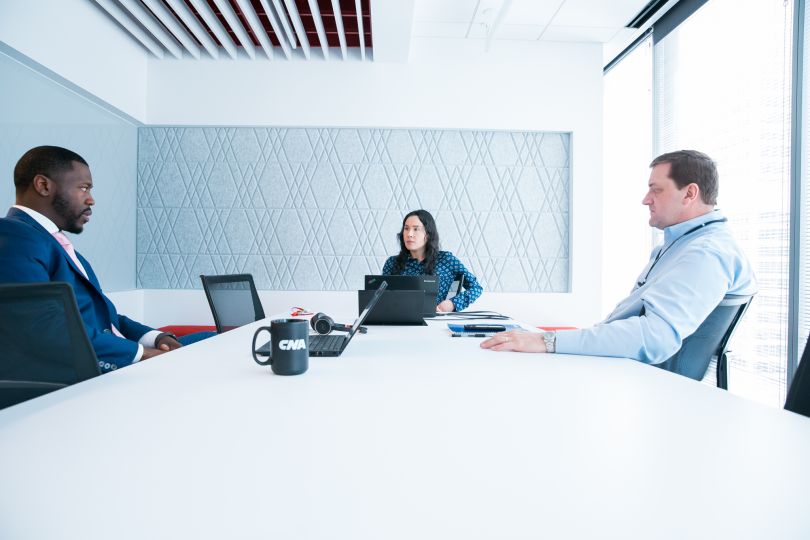 three CNA employees working together at a long white conference room table