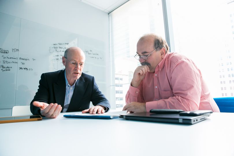 two CNA employees looking over document with whiteboard in the background