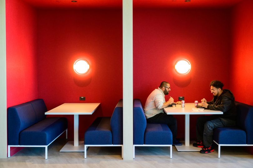 Two CarGurus employees meet in a cafe booth in the company’s new global headquarters inside Boston’s new Lyrik Back Bay project at 1001 Boylston Street. 