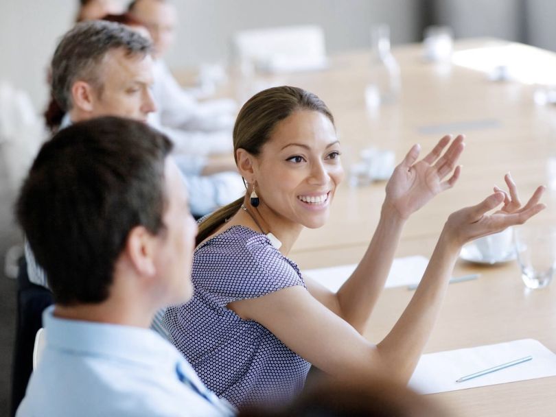 A Cencora team member smiles and gestures in a meeting room.