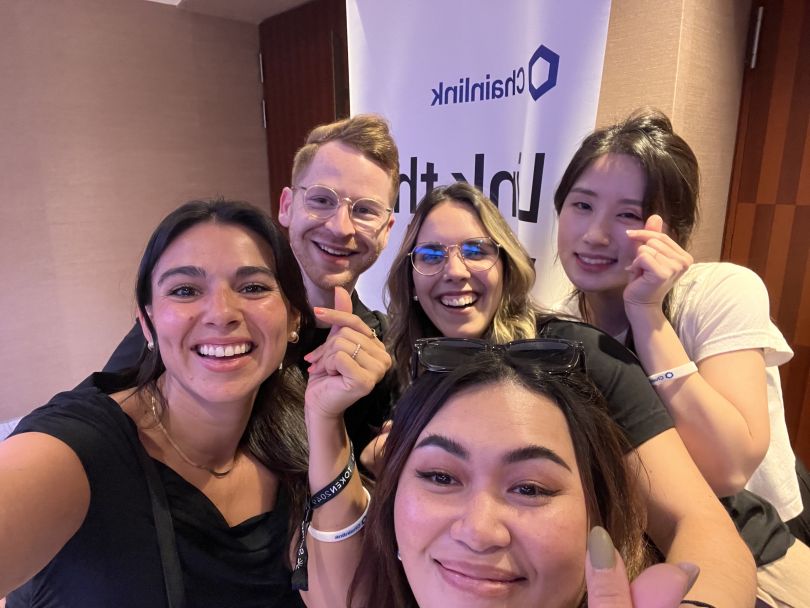 Chainlink Labs employees smile and make hearts with their fingers in a group selfie.