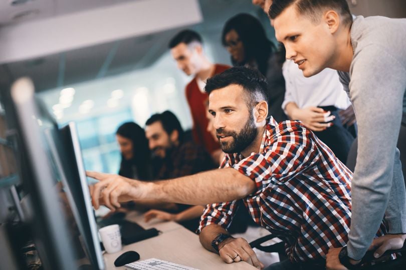 A software programming and another team member looking at a monitor collaborating on a project