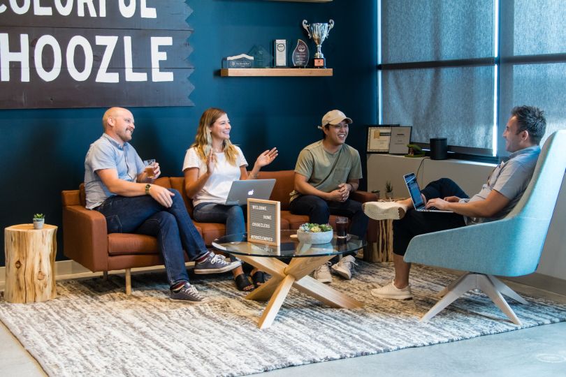 Colleagues laugh while sitting in Choozle's reception area, decorated in blue and teal tones