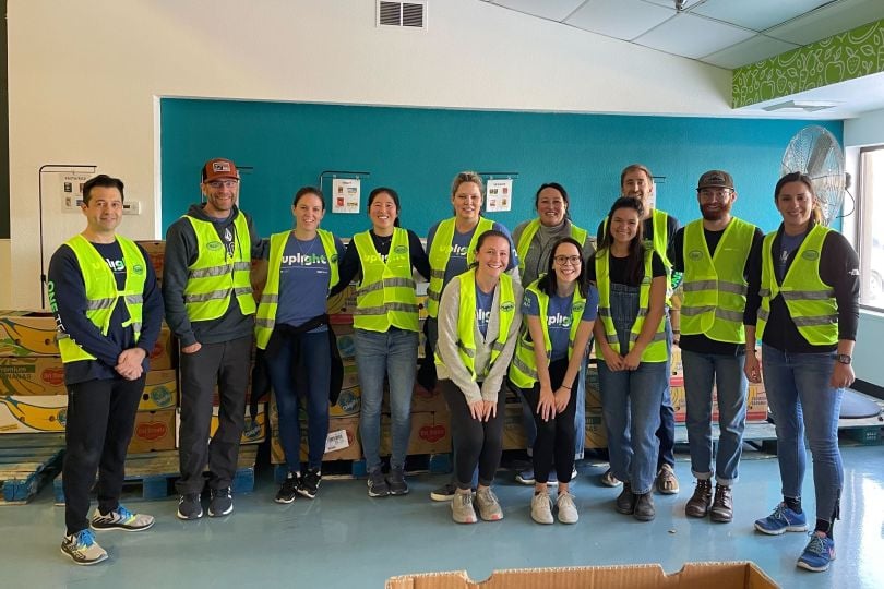 indoors team photo with team members wearing neon green safety vests