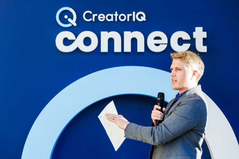 Profile shot of Conor Begley talking into a microphone in front of a backdrop reading “CreatorIQ Connect.”