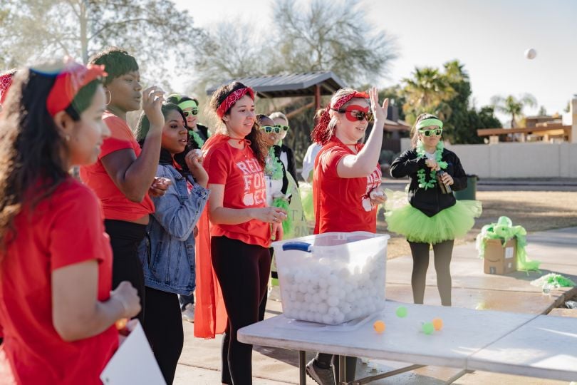 Team members dressed in costumes playing a game with ping pong balls.