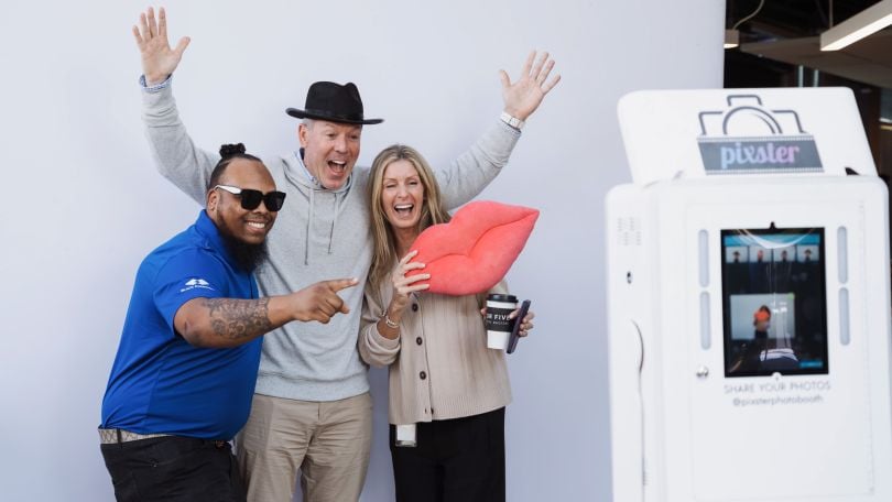 A group of Achieve employees pose together in front of backdrop