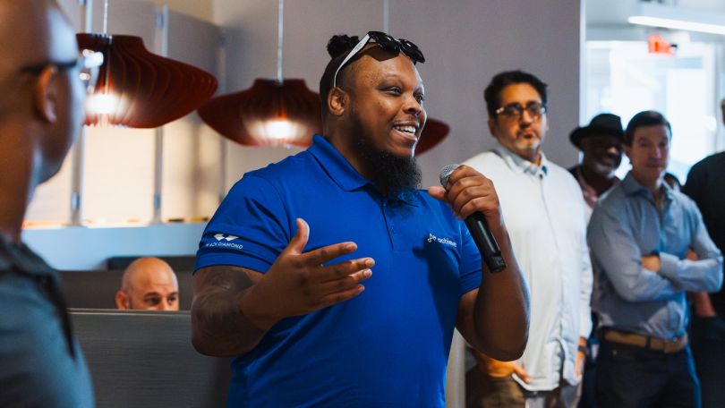 A photo of an Achieve employee speaking to a crowd 