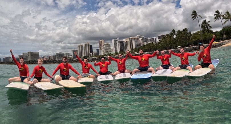 Several Doximity team members pose for a photo while on surfboards in the ocean