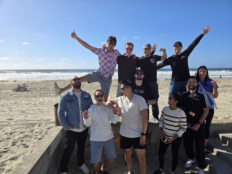 Doximity team members make silly poses for a group picture on a beach