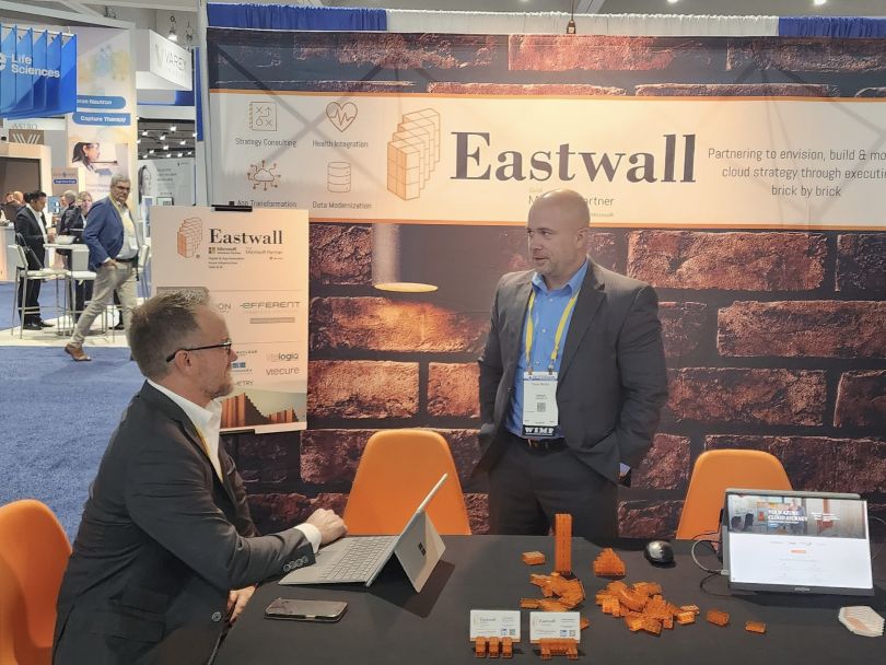 Two Eastwall team members conversing at the company booth at a conference. 