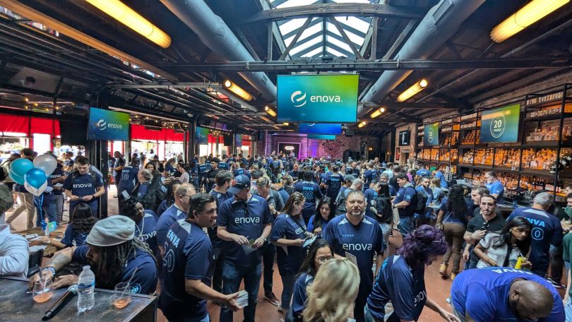 Enova coworkers wearing company-branded shirts gathered together in a large event space