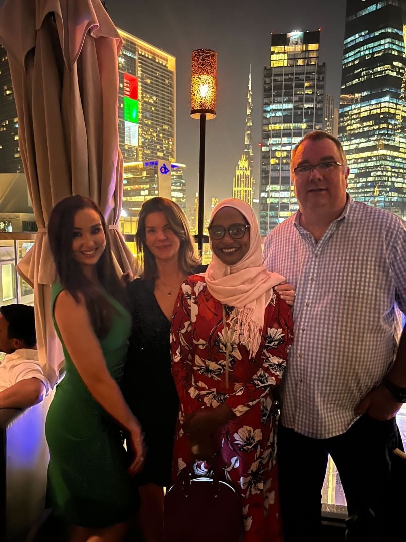 Eventus team members smiling and standing outside at night with skyscrapers in the background.