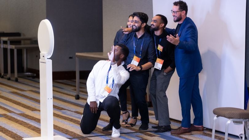 Candid of five FourKites team members posing at a photo booth setup