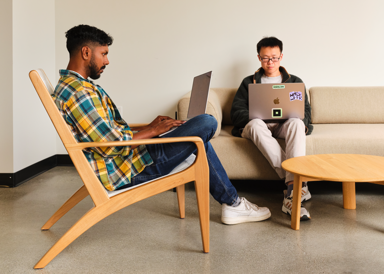 Two developers working in the Roblox platform on a laptop screen 