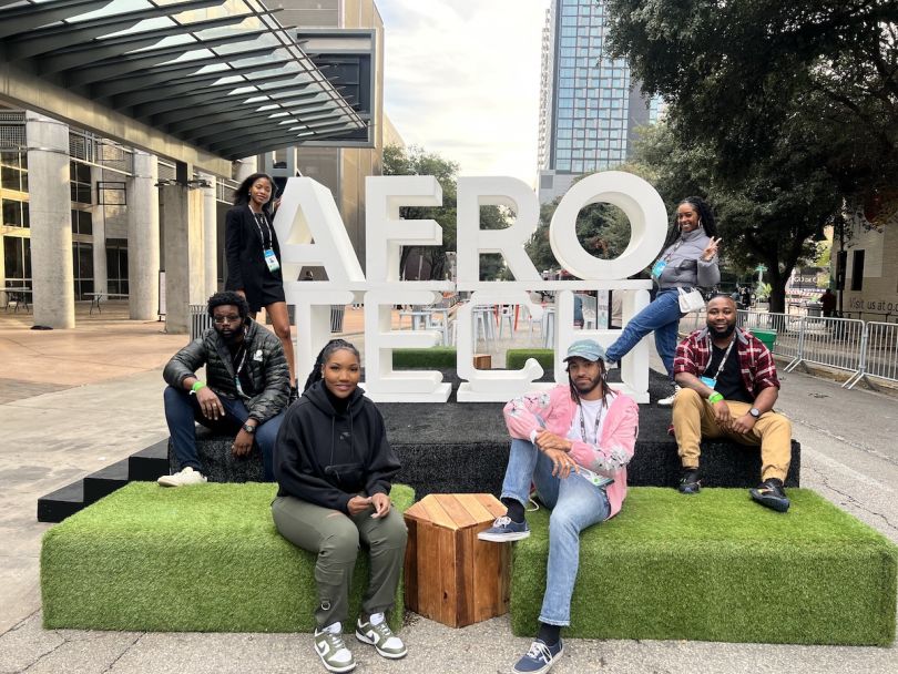 Six people sit around a sign that says Afro Tech