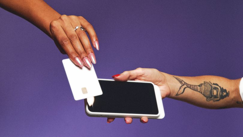 A photo of two hands, one paying via a tap card on a phone to show the idea of point of sale at GlossGenius