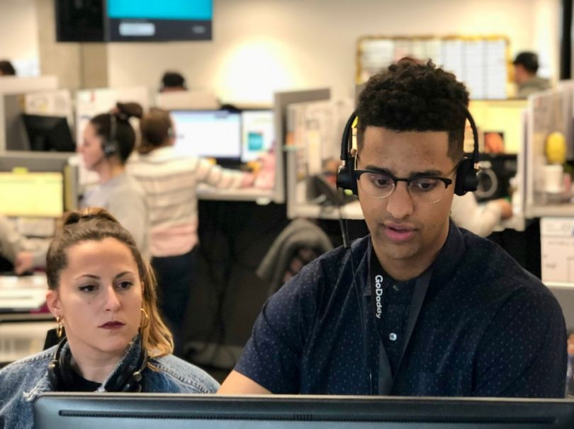 GoDaddy employees looking at a computer monitor