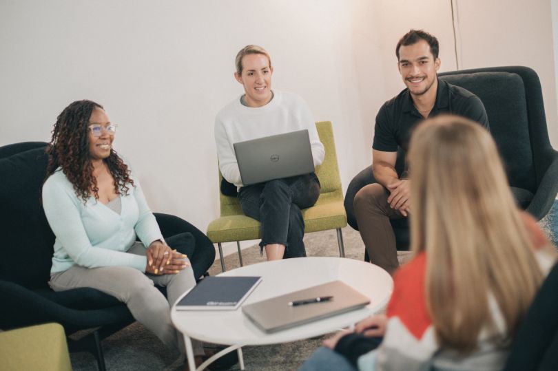 GoHealth employees meet around a coffee table in a modern office. 