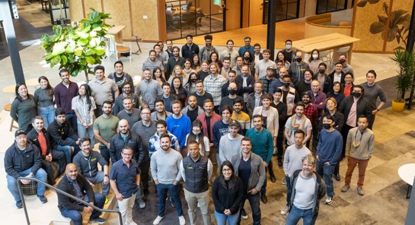 Large group photo of GoodRx team members in office, looking up at camera above.