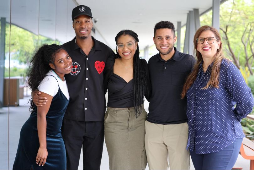 Five GoodRx team members pose for a group photo, arms around one another, on a covered outdoor patio.