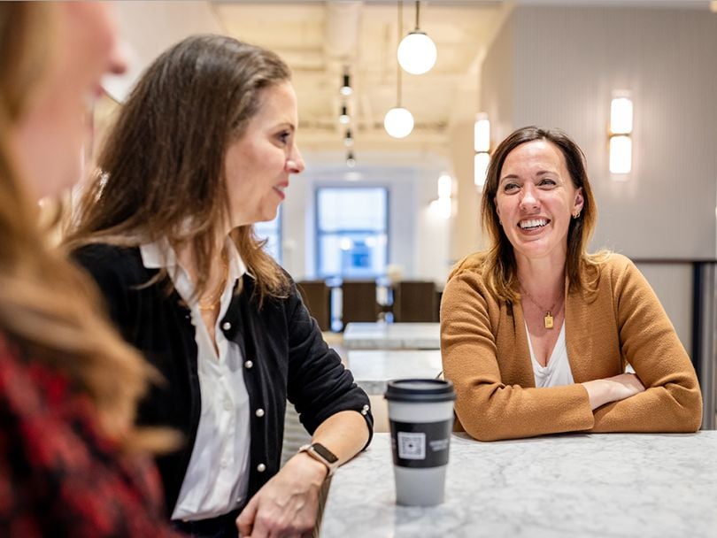  10Pearls team members sitting at a table together and laughing.