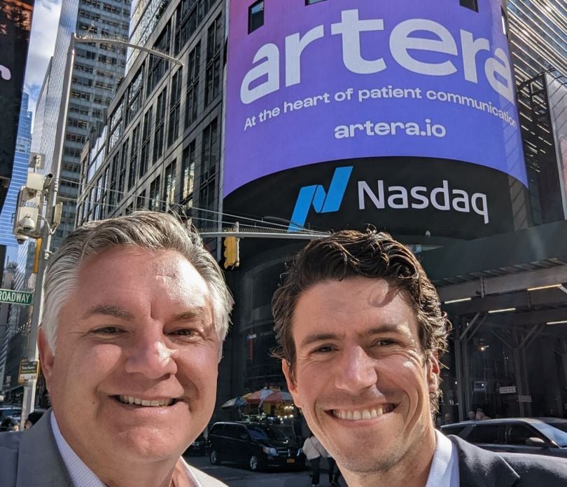 two men in front of digital NASDAQ board announcing artera rebrand