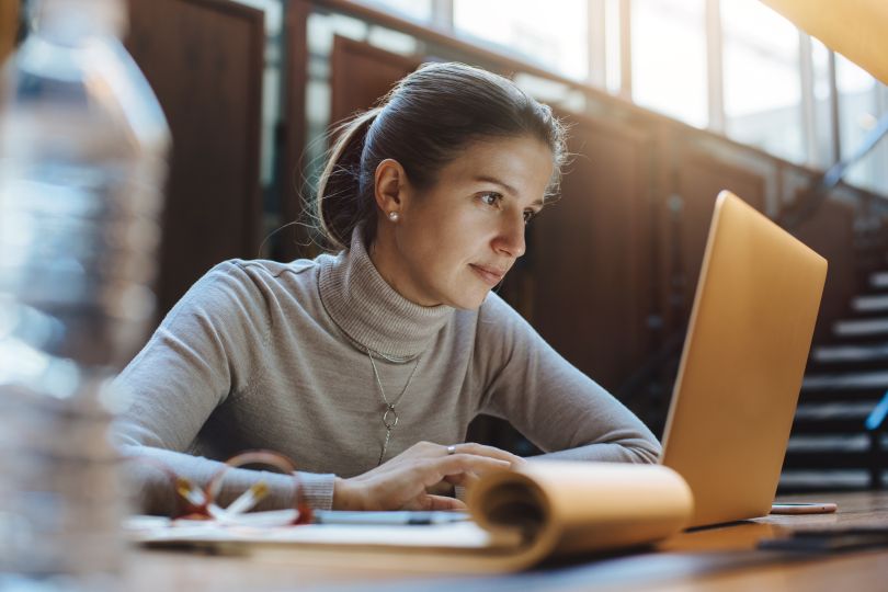 Adult woman engaging in online learning in front of a laptop