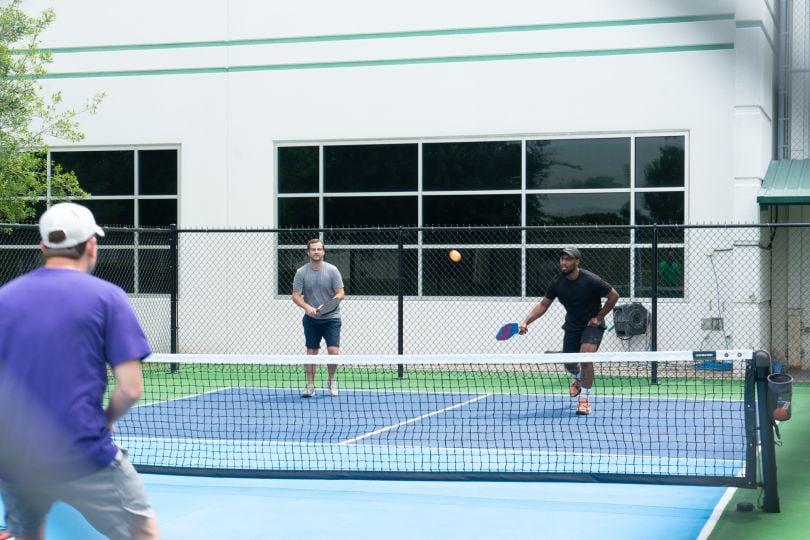 Three HCSS team members playing pickleball together on an outdoor court