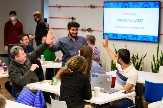 CarGurus employees high-five in an open office