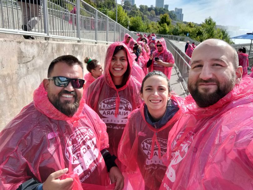 Customer.io team members in red ponchos take group selfie while waiting for their Niagra Falls tour.