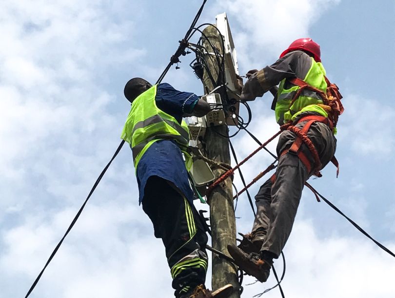 SparkMeter workers install the company's grid visibility platform to an electricity pole.