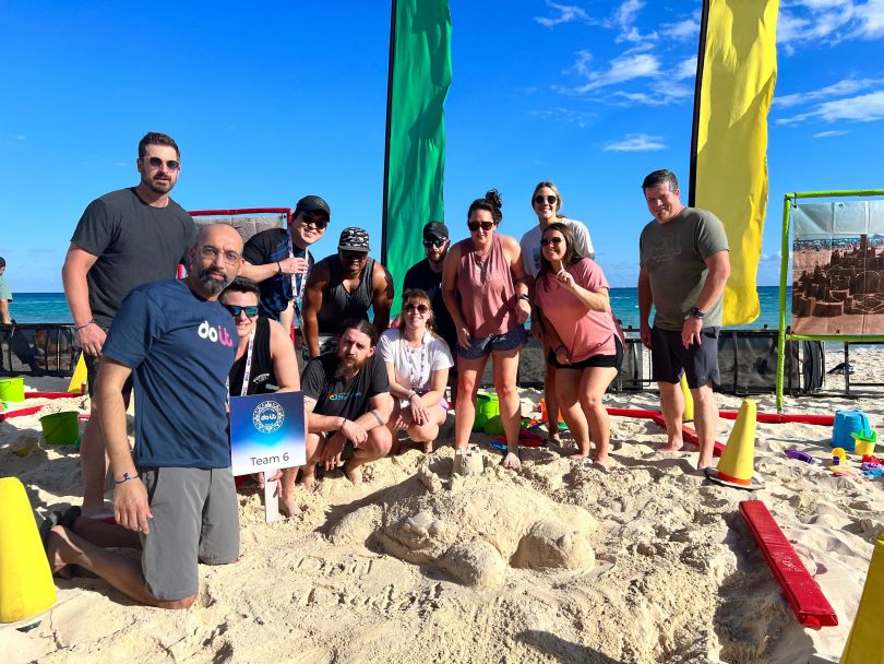 DoiT employees building sand structures at a team event on the beach