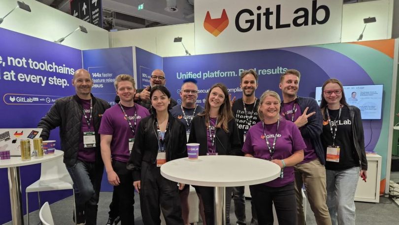 GitLab employees in front of a sign. 