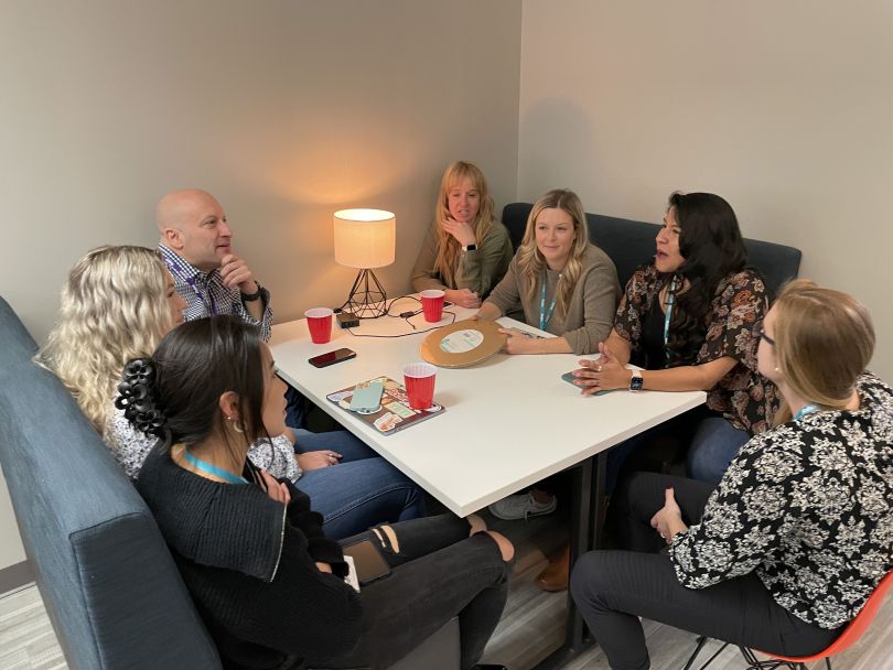 group of people sitting around a white square table