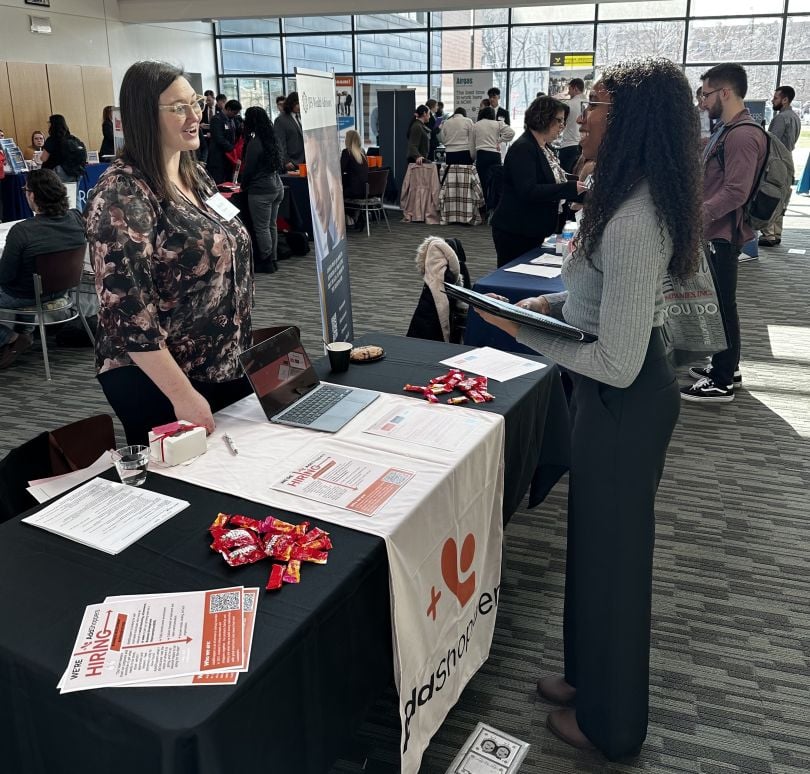 AddShoppers table at event with employee speaking to someone