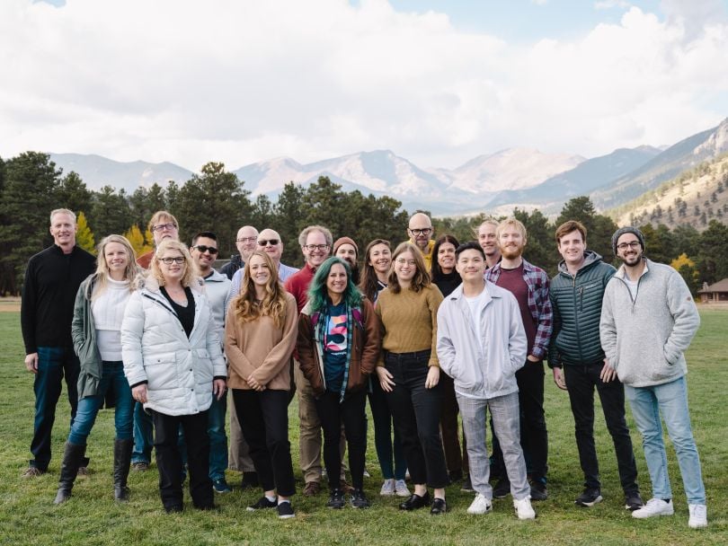 InspiringApps team members pose for a group photo against a mountain backdrop. 