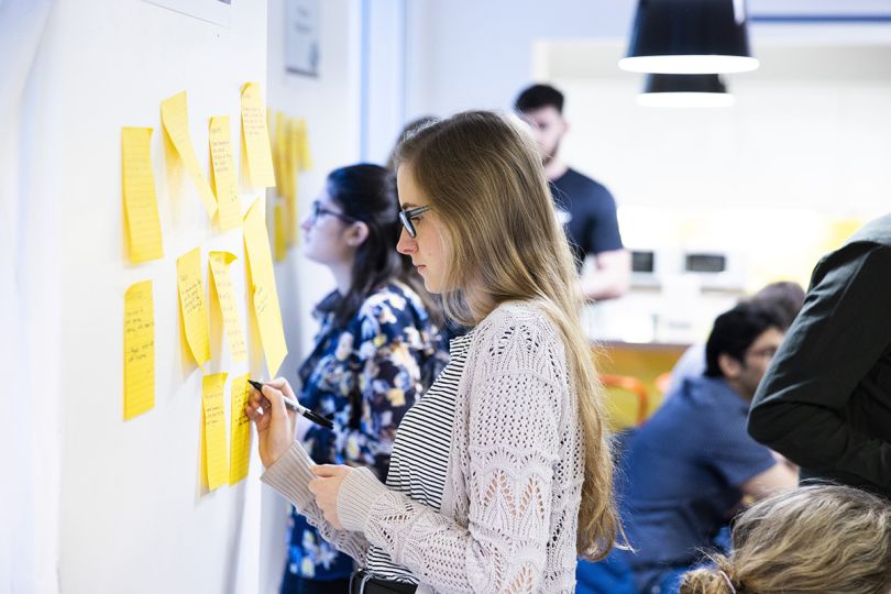 JPMorgan Chase team member writing on post-it notes on a whiteboard