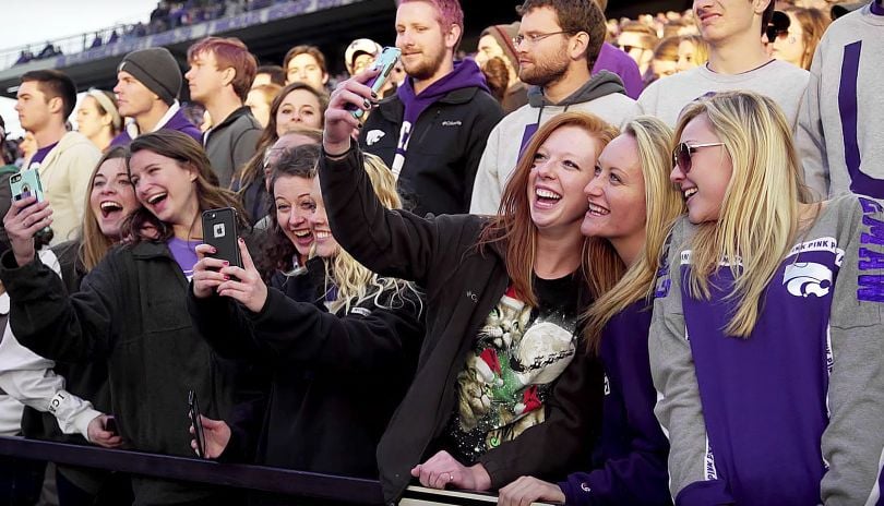 photo of people in the crowd at a sports stadium, with some taking photos