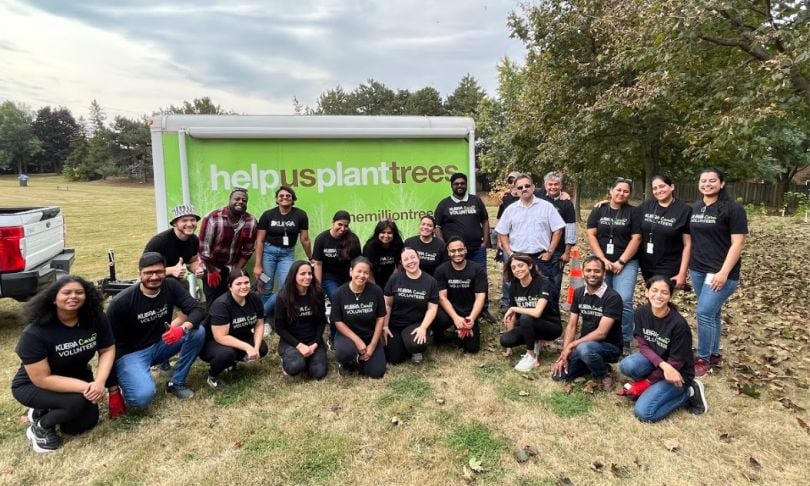 KUBRA team members gather at a volunteer event and wear matching t-shirts. 