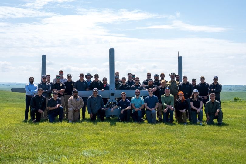 A group of Shield AI employees and U.S. Air Force customers stand in front of three V-BAT drones.